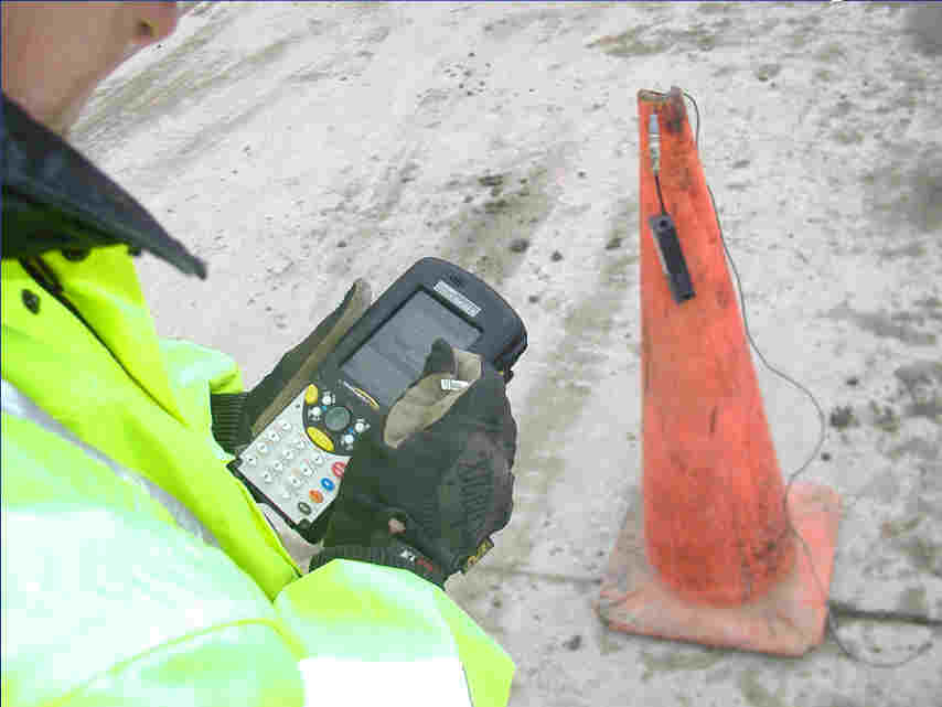 Wireless sensor on a paving project, hung over a cone to stay clear of standing water